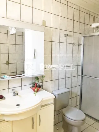 Banheiro com revestimento de azulejos brancos e pias brancas.