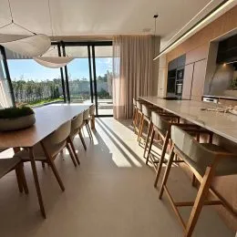 Sala de jantar ampla com mesa longa e portas de vidro que dão acesso ao exterior.