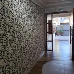 Parede interna com revestimento de papel de parede de folhagens escuras.