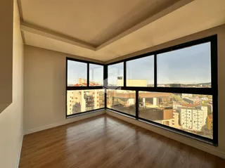 Sala com grandes janelas oferecendo vista da cidade.