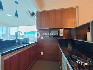 Vista da cozinha com armários de madeira e bancadas escuras.