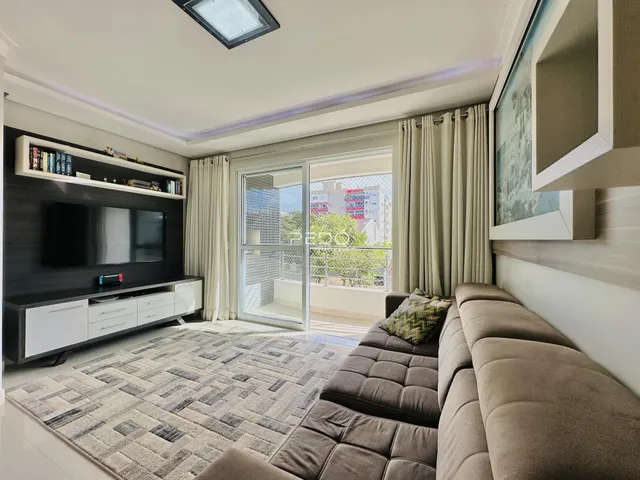 Sala de estar moderna com sofá e televisão em um apartamento no Brasil.