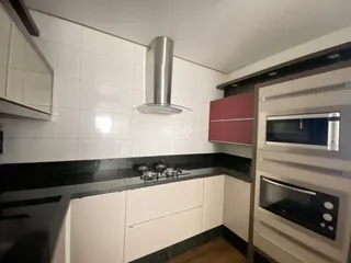 Cozinha moderna com armários brancos e bancada escura.