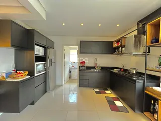 Foto de uma cozinha moderna com armários escuros e piso claro.