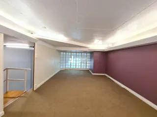 Corredor interno com piso de carpete e paredes em tom de rosa.