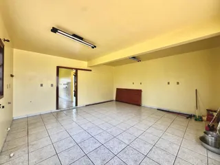 Sala ampla com piso de cerâmica e parede amarela clara.