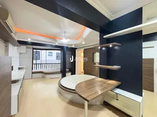 Interior de uma sala de estar moderna com piso de madeira clara e paredes escuras.