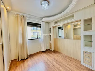Sala de estar com piso de madeira e cortinas claras.