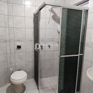 Foto de um banheiro com revestimento cerâmico e box de vidro.