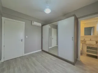 Sala de estar com piso de madeira clara e ar condicionado instalado.