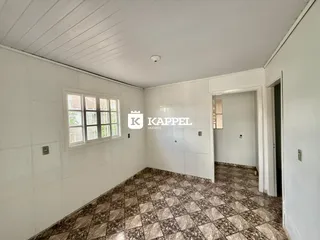 Esta é uma sala interna com paredes brancas e piso de ladrilhos marrons.