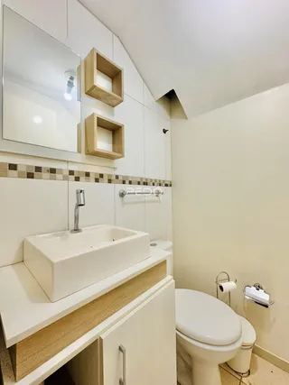 A foto mostra o interior de um banheiro com bancada e vaso sanitário.