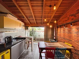 Imagem de uma cozinha e sala de jantar com teto de madeira e parede de tijolos aparentes.