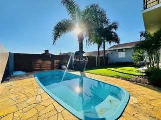 Vista externa de uma piscina e jardim com palmeiras ao fundo.