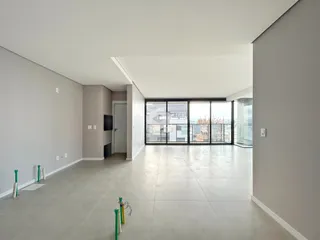 Interior de um espaço amplo com piso claro e grandes janelas de vidro.