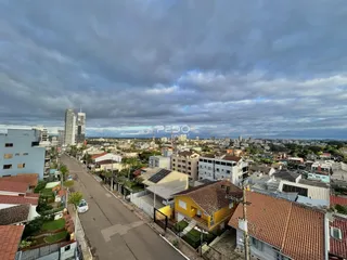 Vista aérea de uma rua residencial em Lajeado, Brasil com casas e edifícios ao fundo.