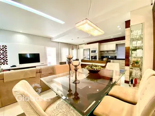 Sala de estar com mesa de vidro e sofás em um apartamento em Lajeado.