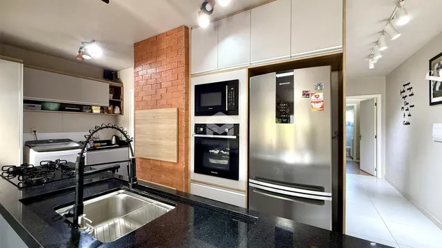Cozinha moderna com armários brancos e parede de tijolos aparentes.