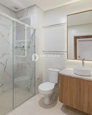 Foto de um banheiro moderno com box de vidro e louças brancas.