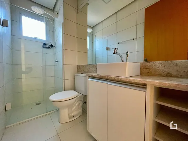 Foto de um banheiro com piso cerâmico e box de vidro.