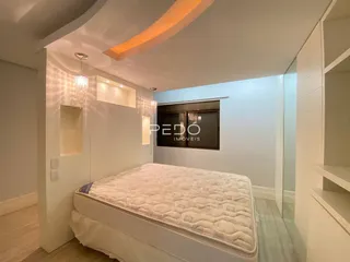 Quarto moderno com cama grande e paredes brancas em um imóvel no Brasil.