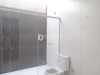 Banheiro moderno com divisória de vidro e piso cerâmico.