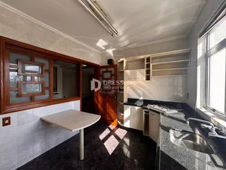 Imagem de uma cozinha com armários de madeira e piso escuro.