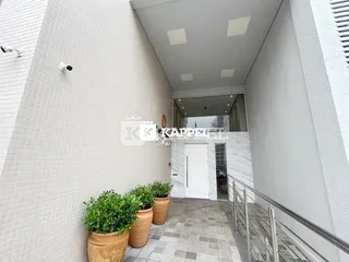 Corredor interno com paredes brancas e piso de ladrilho.