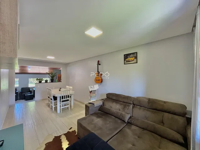 Sala de estar e jantar com sofá e mesa de jantar em ambiente claro.