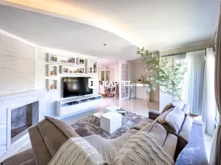 Sala de estar com sofá grande e televisão montada na parede.
