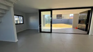Sala de estar ampla com piso claro e porta de vidro que dá acesso a um pátio.