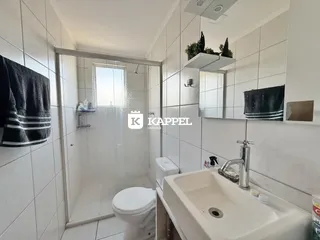 Banheiro com revestimento branco e box de vidro.