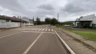 Vista externa de uma rua residencial em Lajeado, com casas e um clube esportivo ao fundo.