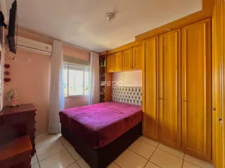 Quarto com cabeceira estofada e armários de madeira em imóvel no Brasil.
