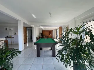 Ambiente interno de uma sala ampla com mesa de bilhar e piso de cerâmica.