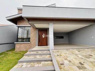 Fachada moderna de uma residência com revestimento de tijolo aparente e área coberta.
