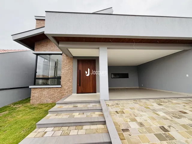 Fachada moderna de uma residência com revestimento de tijolo aparente e área coberta.
