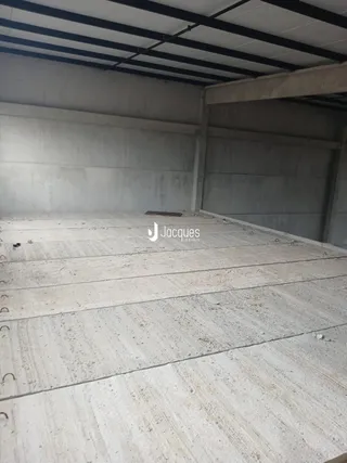 Foto de um espaço interno com piso de concreto e estrutura exposta.