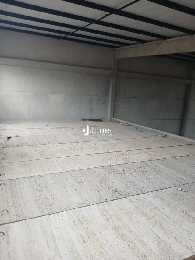 Foto de um espaço interno com piso de concreto e estrutura exposta.