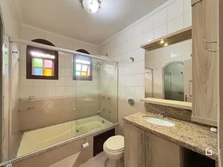 Foto de um banheiro com banheira e box de vidro.