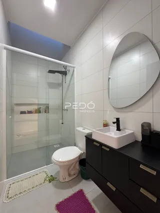 Banheiro com box de vidro e piso cerâmico.