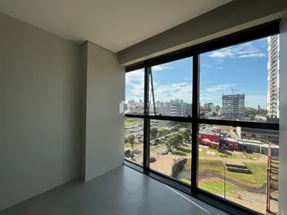 Vista de uma sala com grande janela de vidro mostrando uma paisagem urbana.