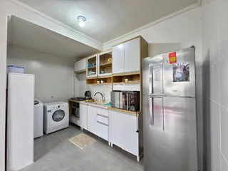 Cozinha com armários brancos e eletrodomésticos de aço inoxidável.