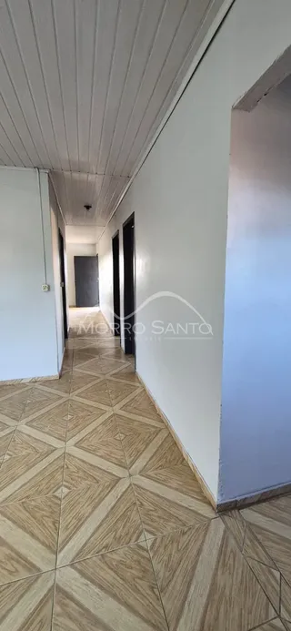 Vista de um corredor com piso de cerâmica clara.