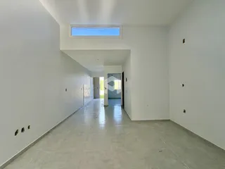 Corredor interno de uma residência com paredes brancas e piso claro.