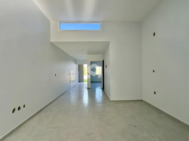 Corredor interno de uma residência com paredes brancas e piso claro.