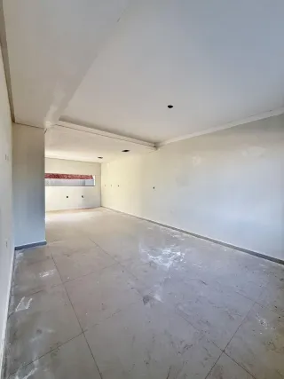 Um corredor amplo com paredes brancas e piso de concreto.