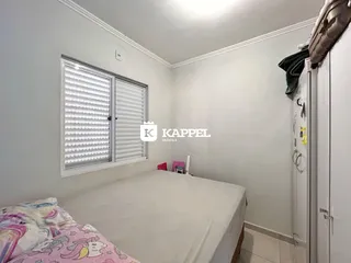 Quarto com cama de casal e janela com persianas brancas.
