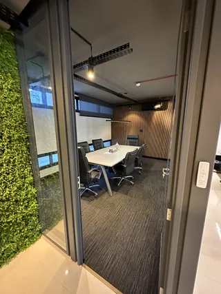 Sala de reunião com mesa e cadeiras em um ambiente moderno.