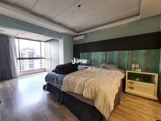 Quarto com grande janela e piso de madeira clara.